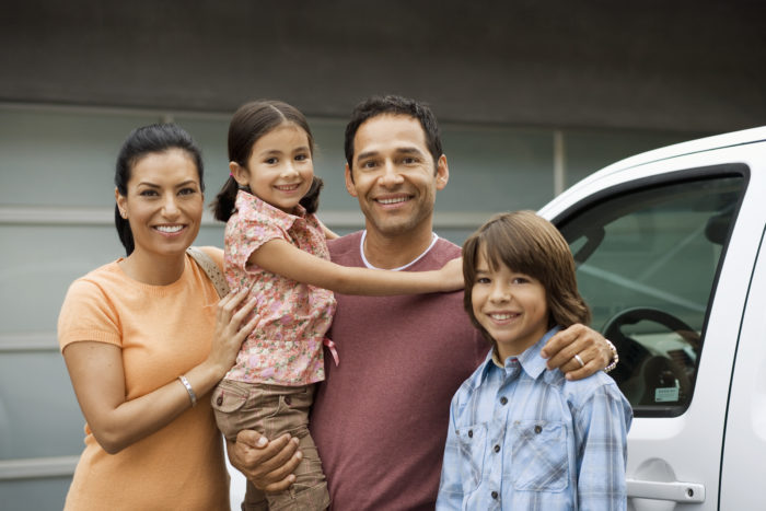 Family standing outside house next to car