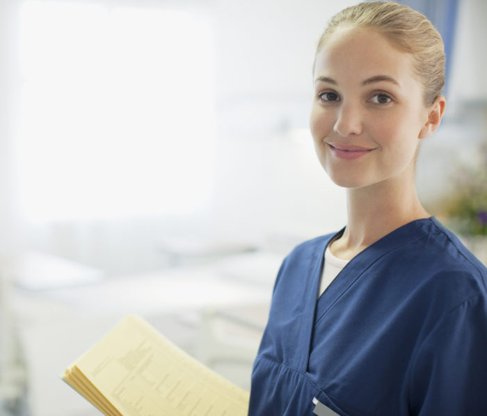 Portrait of smiling nurse holding medical record in hospital room